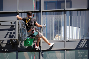 Worker washes the window of residential building. Windows cleaner on the high rise building facade