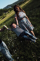 Mom, dad and son on walk in chamomile field in summer. Young parents hold their young son with both...