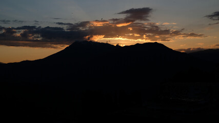 Silhouette of mountains against the background of a sunset or dawn sky. The sun went down behind the mountains. View of moody sunset in the mountains.