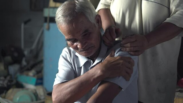 Footage B roll of Older man shoulder pain. Older man receiving a shoulder massage with his wife. His wife massage a shoulder after hard working. Thai culture and real.