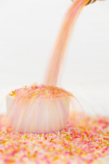 ice cream sprinkles pouring into a container shot against a white background