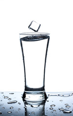 Ice in glass of water with splash on white background