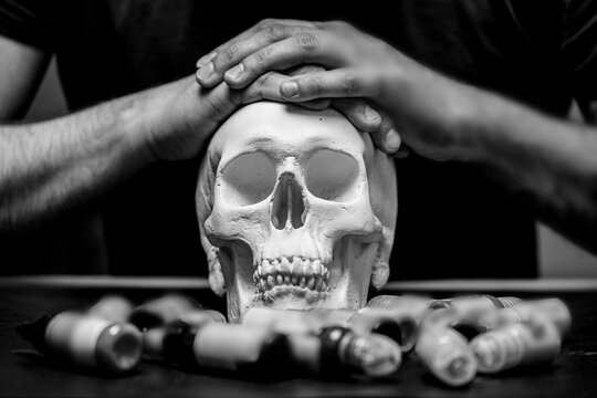 Tattoo artist folded hands on plaster skull surrounded by typewriter ink, black and white photo