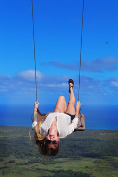 happy smiling girl with long hair in a seesaw on top of a hill on the coast of the Atlantic Ocean