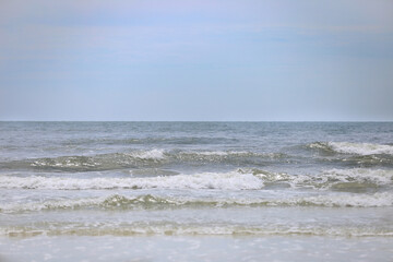 Ocean waves and pelicans flying low to the tide in Crescent Beach, St. Augustine, FL