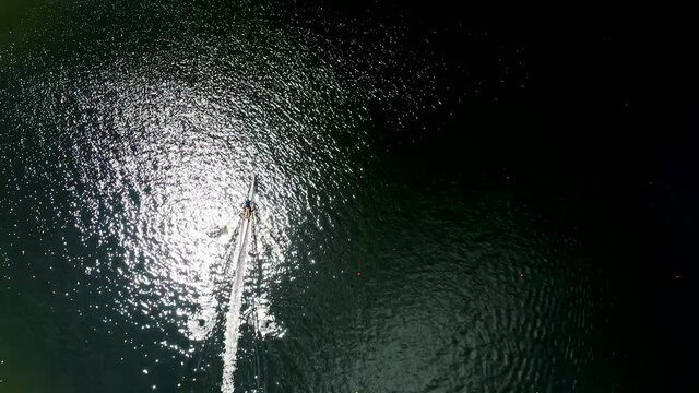 

Aerial: Single scull rowing  on  lake with  ripples on the water surface. Beautiful reflections on the water
Trakai, Lithuania, 