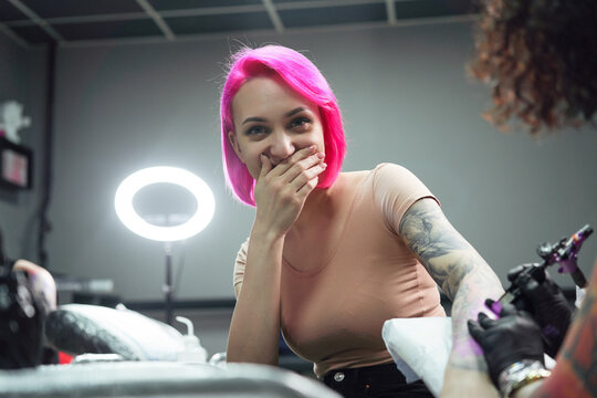 Female tattooist making tattoo on hand with machine in salon
