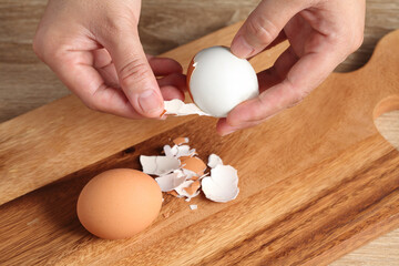 Chef peeling boiled egg on cutting board in kitchen