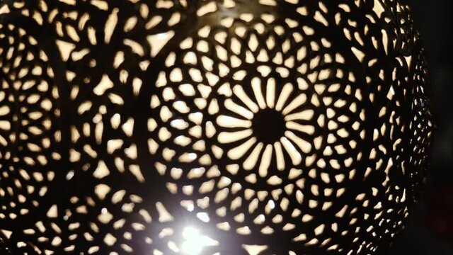 Abstract closeup of a lit, Moroccan, Arabic brass lamp with intricate floral pattern. Concept for Moroccan and Arabian lamp design. Abstract background footage, moving from blur, defocused into focus.