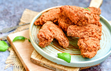 
 Crispy  deep fried   chicken strips and wedges potato. Breaded  with cornflakes chicken  breast fillets  with chilly peppers and fresh   basil on wooden rustic background