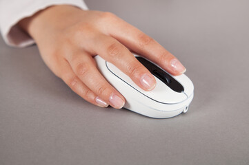 Woman's hand with computer mouse on table.