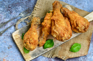 
 Crispy  deep fried home made    chicken   legs Breaded  with  almond flour chicken  breast fillets  with chilly peppers and fresh   basil on wooden rustic background. Ketogenic diet food