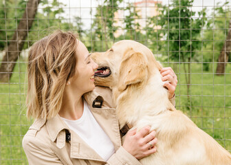 The mistress girl sits on a bench with her dog of the Golden Retriever breed and hugs
