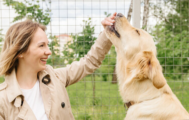 The hostess girl sits on a bench with her golden retriever dog and gives her a treat