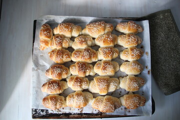 Just baked croissant rows on oven tray with baking paper and textile tack on white background
