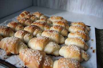 Just baked hot croissants on oven tray with baking paper and textile tack on white background