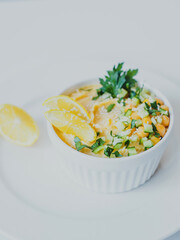 Hummus from chickpeas, with olive oil, lemon, sesame seeds and cucumbers, on white background.