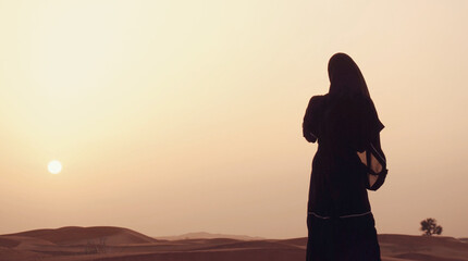 Portrait of a young Arab woman wearing traditional black clothing during beautiful sunset over the...