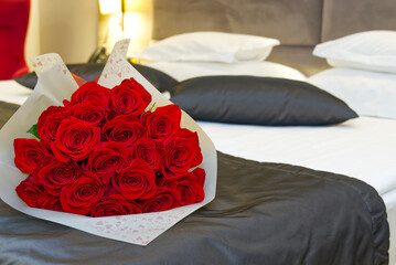 Bouquet of red roses on the bed in a hotel room. Romantic meeting of guests at the hotel honeymoon....