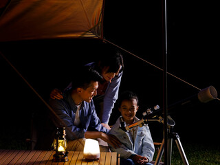 A happy family of three using telescopes outdoors