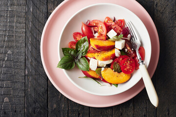 Salad with tomatoes, peach, red onion, cheese and basil.