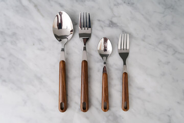 set cutlery of spoon, and fork, with a wood vintage handle on the marble table.