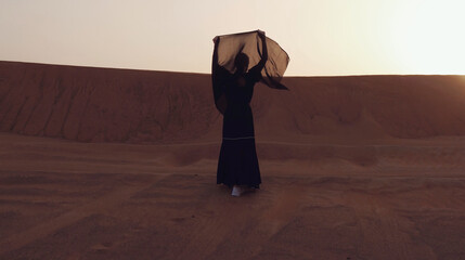 Portrait of a young Arab woman wearing traditional black clothing during beautiful sunset over the...