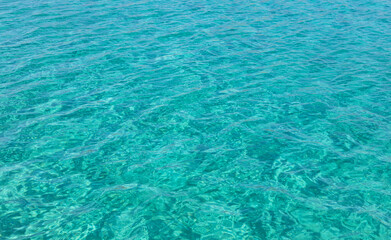 Fototapeta na wymiar Sea surface turquoise blue color background, some reflections. Calm crystal clear water with small ripples.