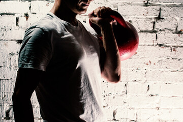 a young man in a white t-shirt holding a kettlebell