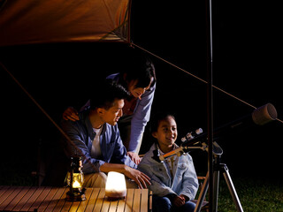 A happy family of three using telescopes outdoors