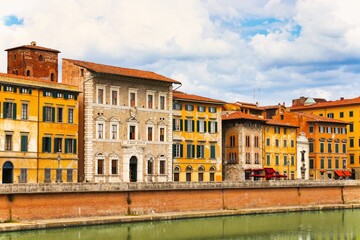 Fototapeta na wymiar A bridge passes over the river and houses on both sides are overlooking the water. Tuscany, Italy, Europe. River Arno quietly passing through Pisa, Italy. Pisa, Arno river, Lungarno view