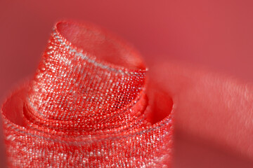 A single coiled ribbon shot on a red background with a vintage Helios lens.  Thin slice of focus on centre of ribbon.  Bubble bokeh