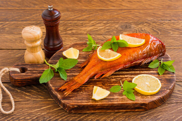 Delicious smoked fish ocean perch on wooden cutting board for healthy food, diet or cooking concept, selective focus