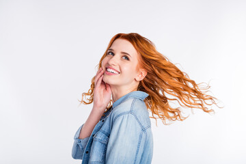 Photo of attractive young dream positive woman look empty space hold hand face fly hair isolated on...