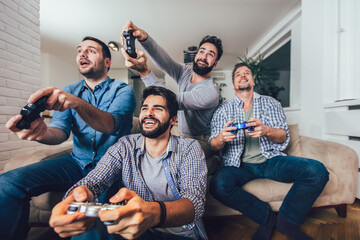 Smiling male friends playing video games at home