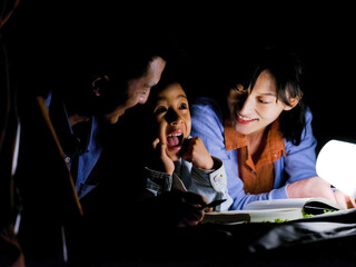 A happy family of three reading and taking notes at night
