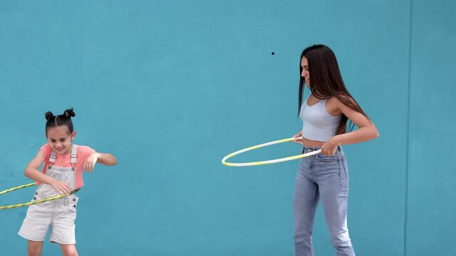 Teenage girl and little sister playing with hula hoops in the city 