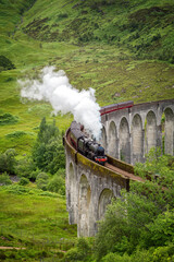 A vintage steam train crosses the Glenfinnan Viaduct, Scottish Highlands