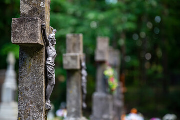 Jesus figurine on the cemetery cross. Picture taken in a soft light, shaded place.
