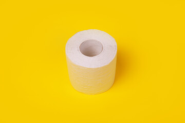 roll of white toilet paper over yellow background