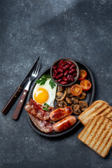 English Breakfast with fried eggs, sausages, bacon, beans, toasts, tomatoes and mushrooms