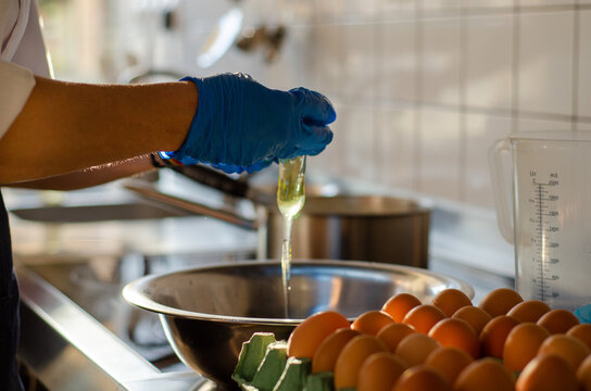 Cook's Hands Cracking Eggs In A Metal Bowl