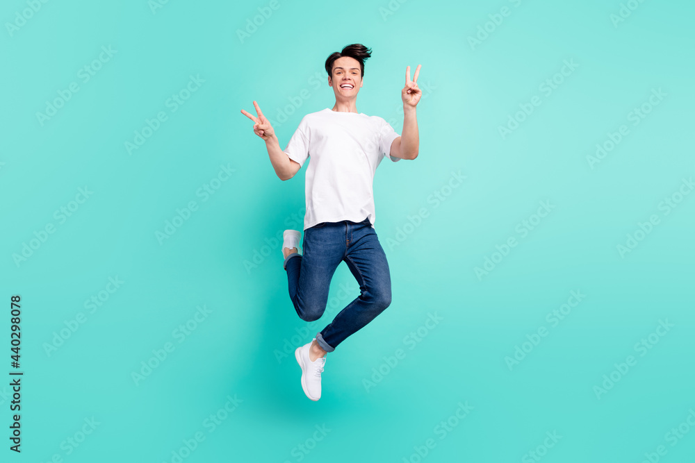 Poster full length body size photo guy jumping showing v-sign gesture overjoyed isolated vivid turquoise co