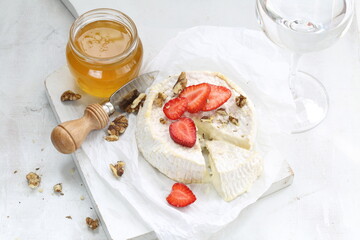 Camembert with strawberries and wine on a white background