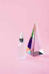 Serum jar with pipette mockup and glass pyramid prism on pink background with copy space, vertical....