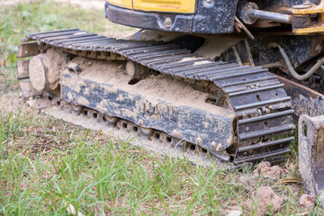 Fototapeta na wymiar Excavator tracks. Old iron caterpillars of the bulldozer of the tractor on the road. bulldozer caterpillar tracks. Black caterpillar tractor grader with the wheels on the ground.