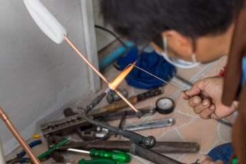 Man hands bends copper pipes by pipe bender. Air conditioner technician hands bends copper pipes by...
