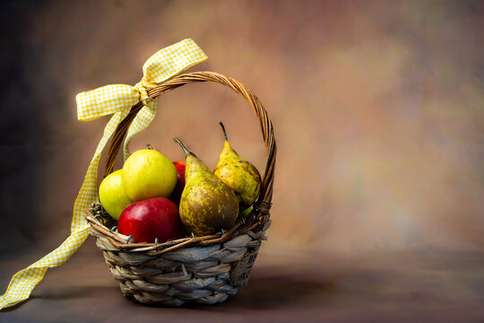 Scena con un cesto di frutta pieno di mele e pere rosse e gialle, legato con un fiocco giallo. Con spazio per scrivere. Alimentazione. Salute. Ringraziamento.