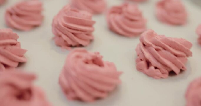 Many red and pink cooked marshmallows lie on the table