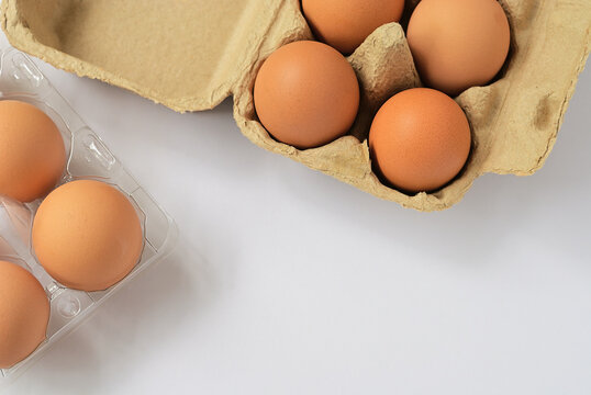 Organic eggs in recycle paper and transparent plastic trays isolated on white background. Fresh eggs protected in tray at ease of use and handle. Top view image with copy space.